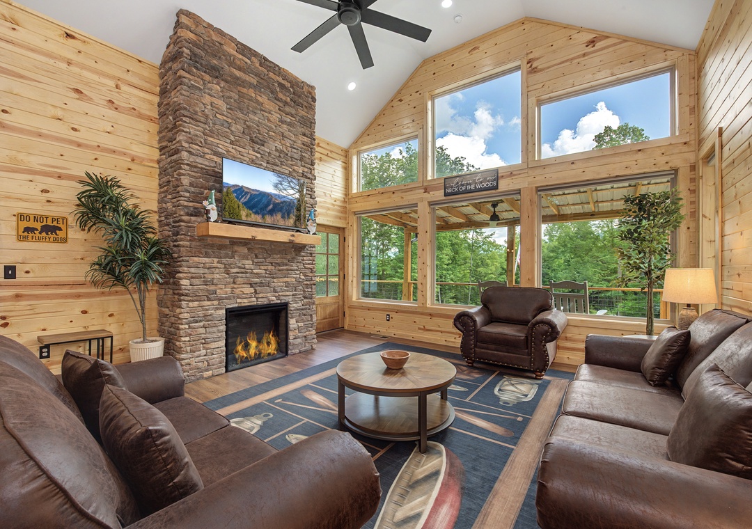Settle into plush leather seating around the stone fireplace, where vaulted ceilings and floor-to-ceiling windows frame lush forest views—your perfect retreat after mountain adventures.