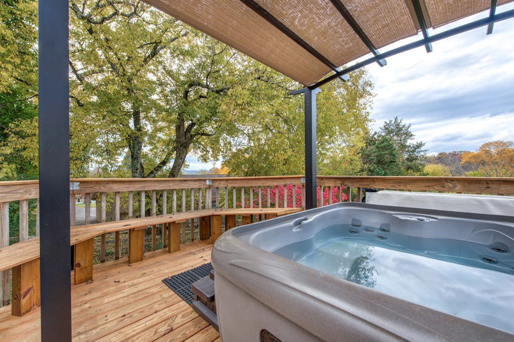 Soak in your private hot tub under the covered deck as autumn leaves paint the hillside in warm hues, offering a peaceful retreat surrounded by nature's beauty.