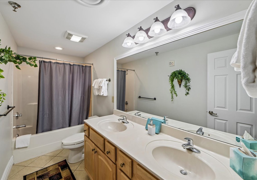 Unwind in your spacious bathroom featuring dual sinks, warm wood vanity, and refreshing tropical touches that make your morning routine feel like a spa retreat.