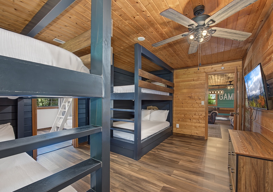 Cozy bunk room with rustic wood finishes and stylish ceiling fan—perfect for family or groups. Everyone gets their own space while staying close together under warm, inviting ceilings.