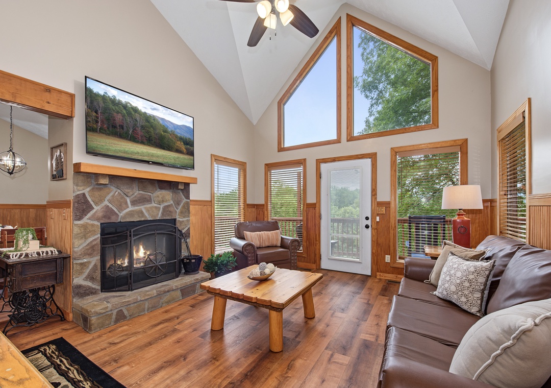 You'll love gathering here—vaulted ceilings frame stunning natural light, while the stone fireplace adds rustic warmth. Step outside through your deck door and take in the peaceful tree views surrounding your retreat.