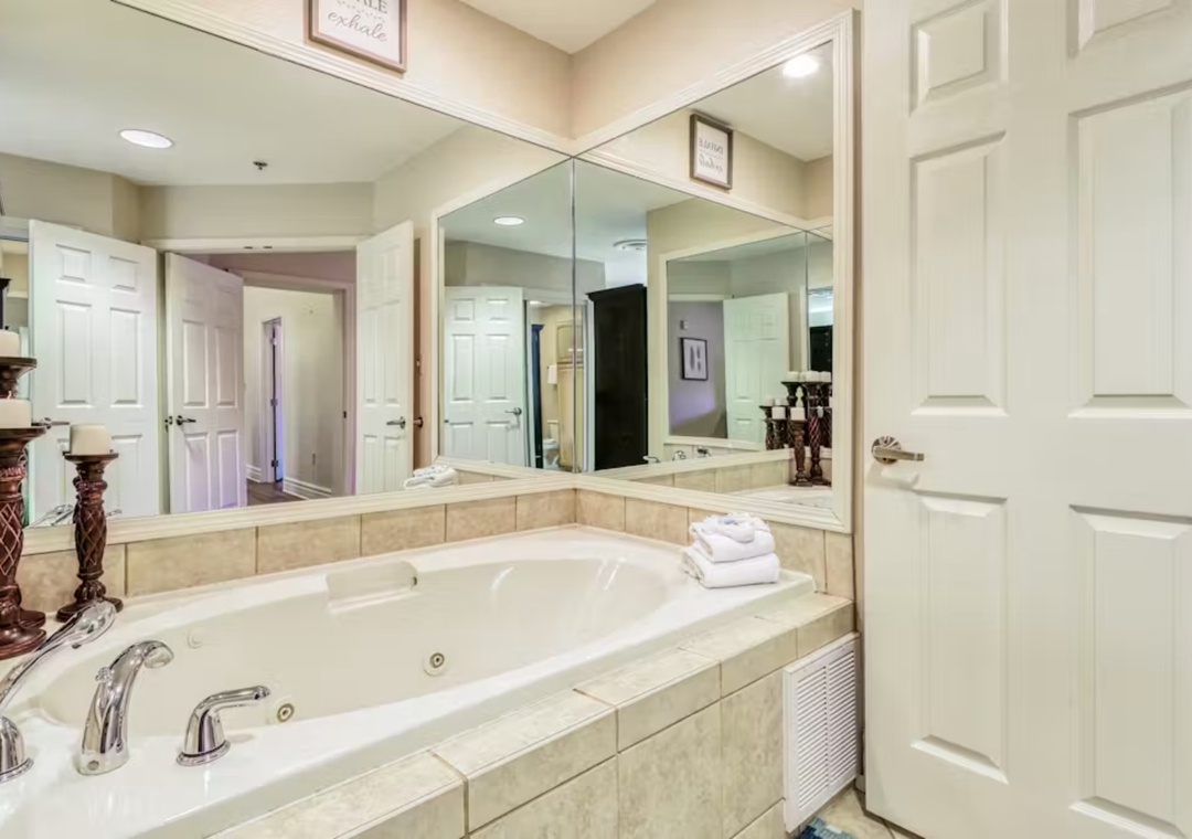 Unwind in your luxurious ensuite bathroom, featuring a spacious soaking tub surrounded by elegant marble and warm ambient lighting for ultimate relaxation.