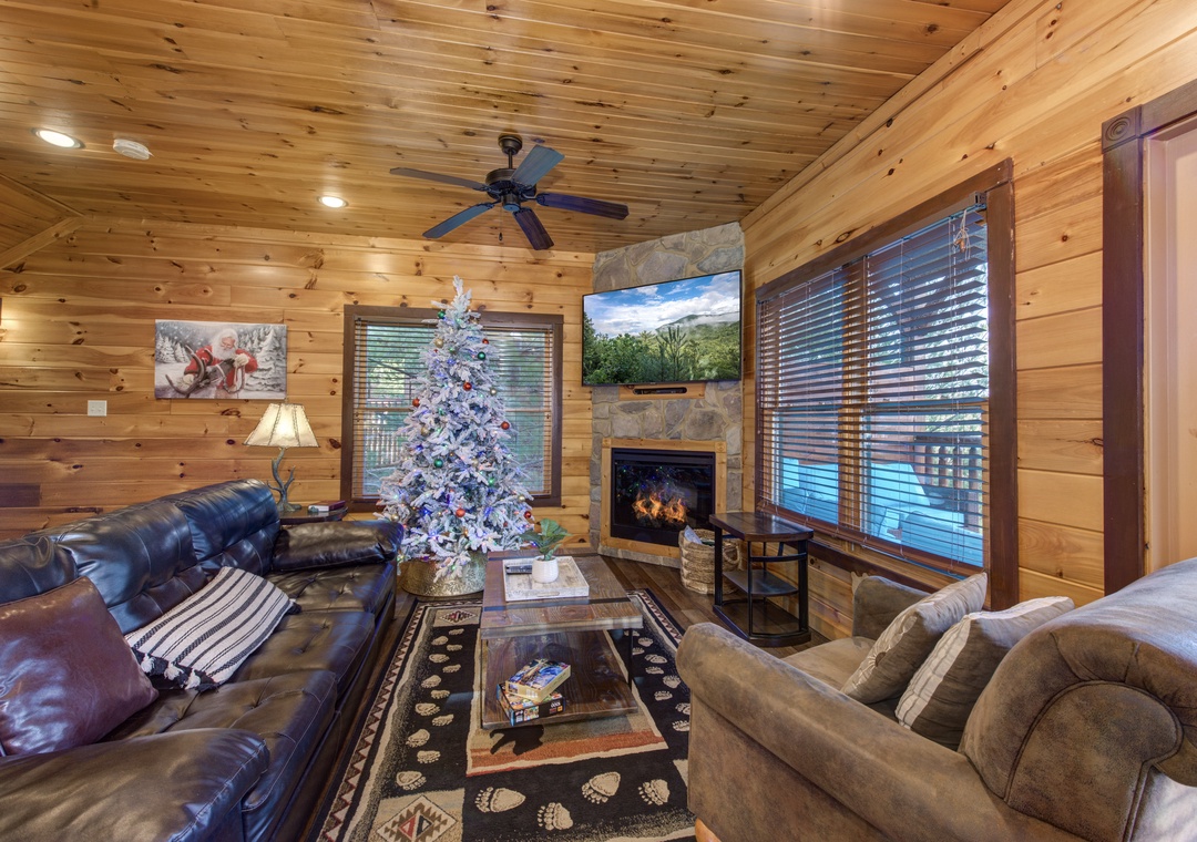 Unwind in your cozy living room with warm wood-paneled walls, plush leather seating, and a stone fireplace—your perfect retreat after exploring the mountains.