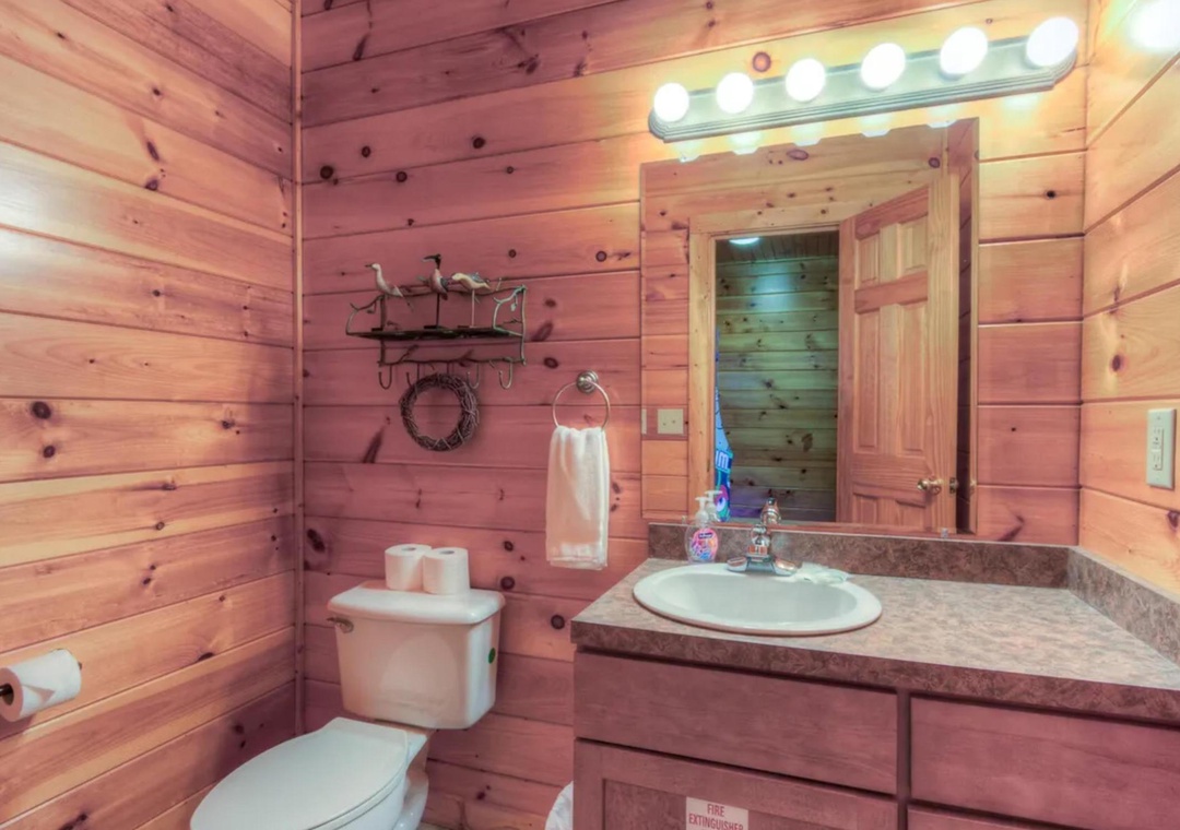 Step into your charming cabin-style bathroom with warm knotty pine walls, granite countertops, and rustic touches that make freshening up feel like a cozy retreat.