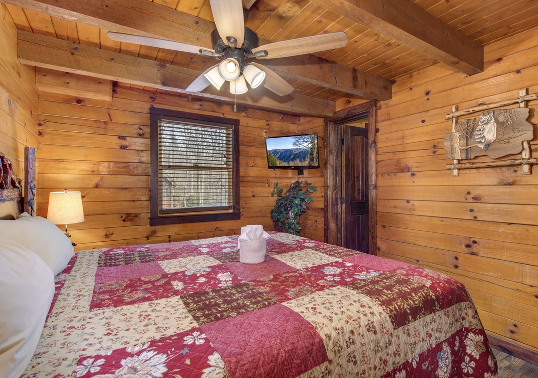 Drift off to sleep in your cozy log cabin bedroom, where rustic wood walls and a charming quilt create the perfect mountain retreat atmosphere.