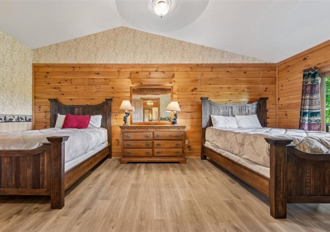 Unwind in this cozy bedroom featuring warm wood paneling and two inviting beds. Picture yourself resting after a day of adventure, surrounded by rustic charm and thoughtful touches that make you feel right at home.