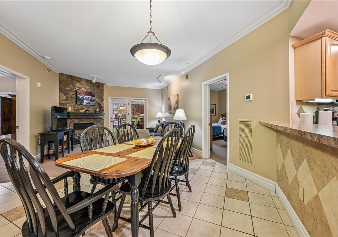 Gather around your elegant dining table for memorable meals with warm stone fireplace ambiance creating perfect evenings together.