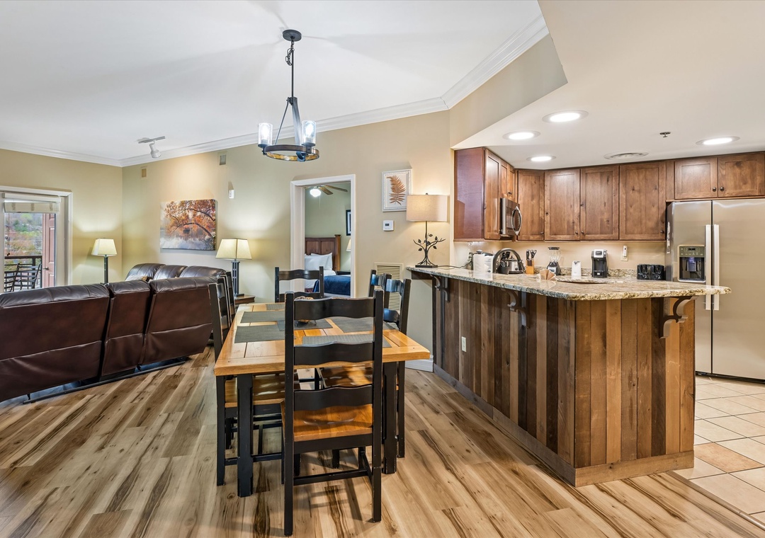 Your open-concept haven features rich wood cabinetry, granite counters, and a cozy leather sofa perfect for memorable vacation moments together.