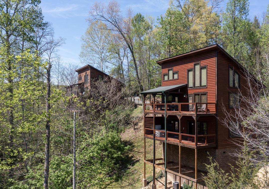 Modern cedar-clad retreat nestled among towering forest trees, featuring multi-level decks and floor-to-ceiling windows for the ultimate woodland escape.