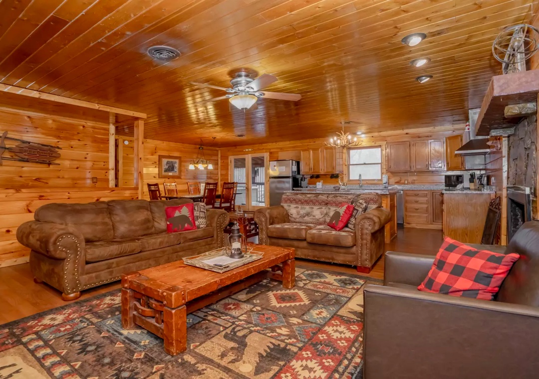 Relax in your cozy cabin's open living area where rustic wood meets comfort—leather sofas and warm lighting create the perfect retreat.