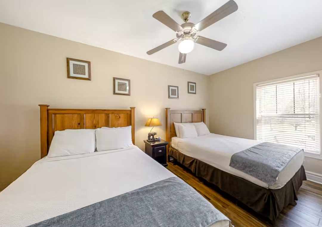 Rest comfortably in your peaceful twin bedroom featuring crisp white linens and warm wood furnishings for a cozy night's sleep.
