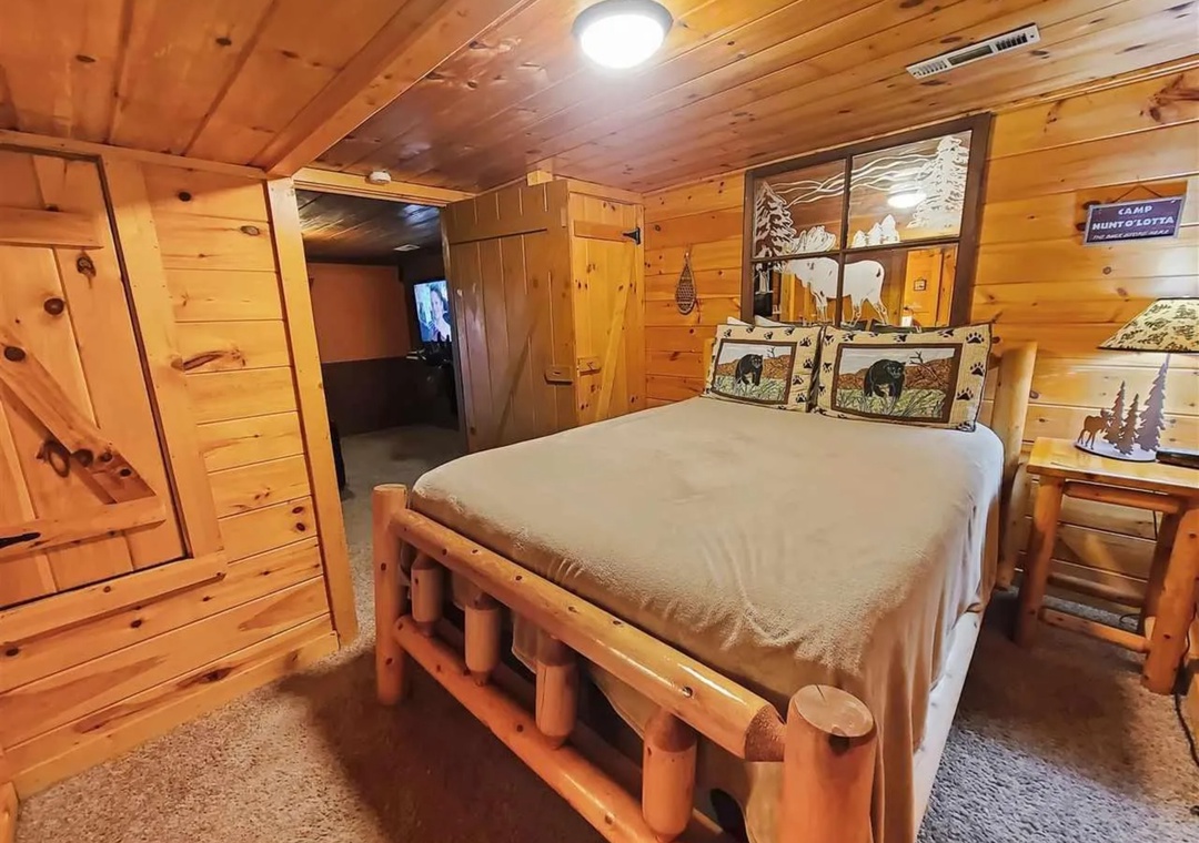 Your rustic log bedroom features handcrafted wooden furniture and charming hunting-themed decor for a cozy mountain retreat experience.