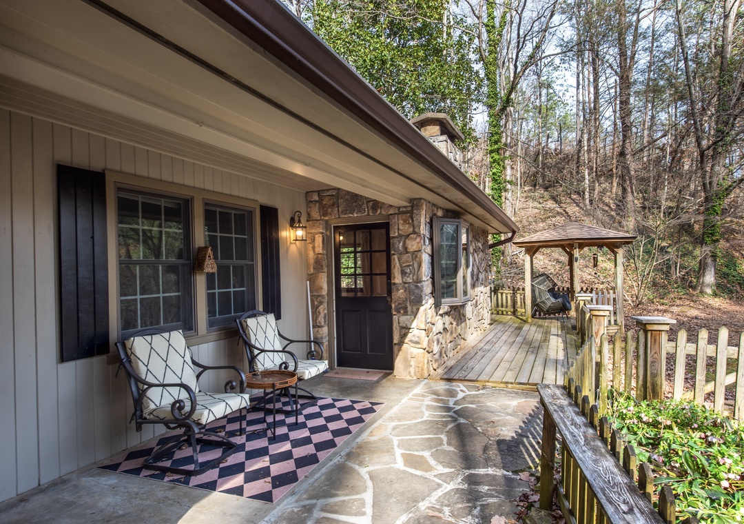 Relax on your private covered patio with comfortable seating and peaceful forest views surrounding this charming stone cottage.