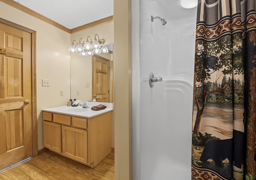 Step into a cozy cabin-style bathroom where warm wood tones meet rustic charm. A peaceful forest scene shower curtain sets the tone for your mountain retreat.