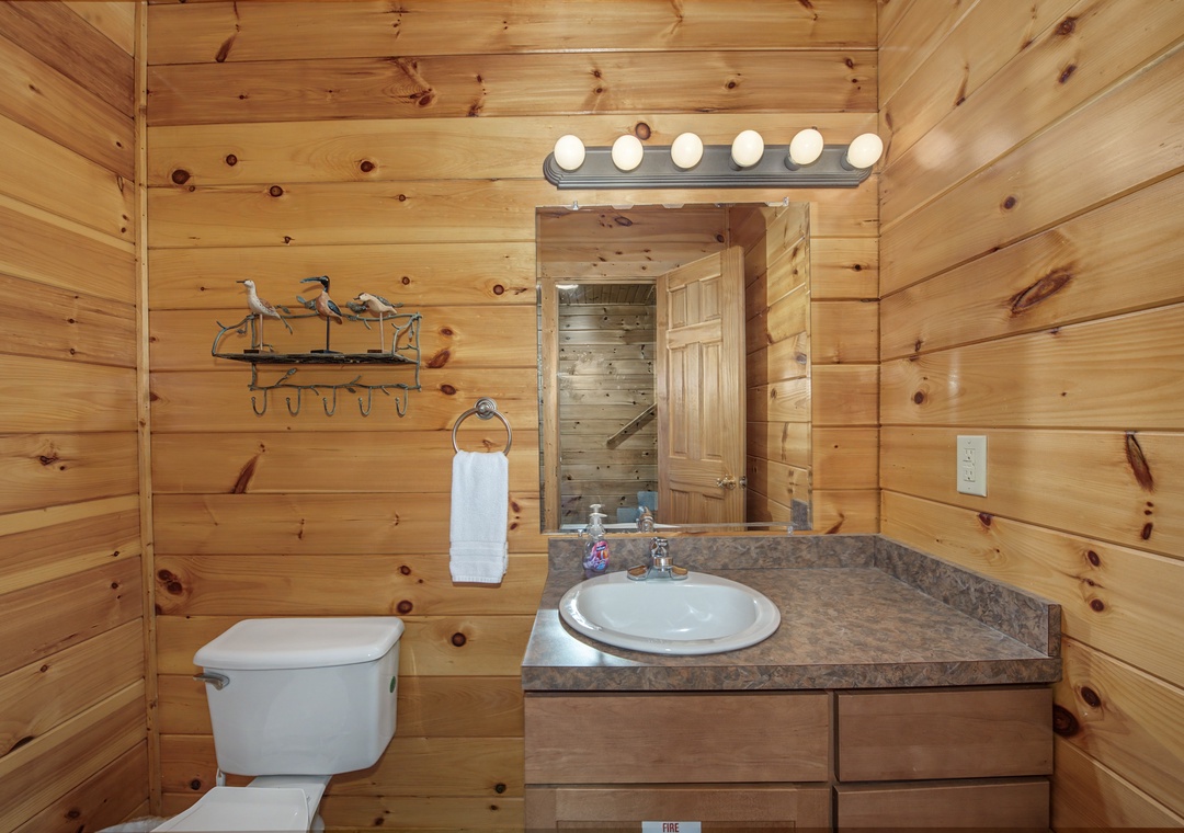 Your bathroom offers rustic warmth with knotty pine walls, granite countertops, and Hollywood-style lighting for getting ready each morning in cozy cabin comfort.