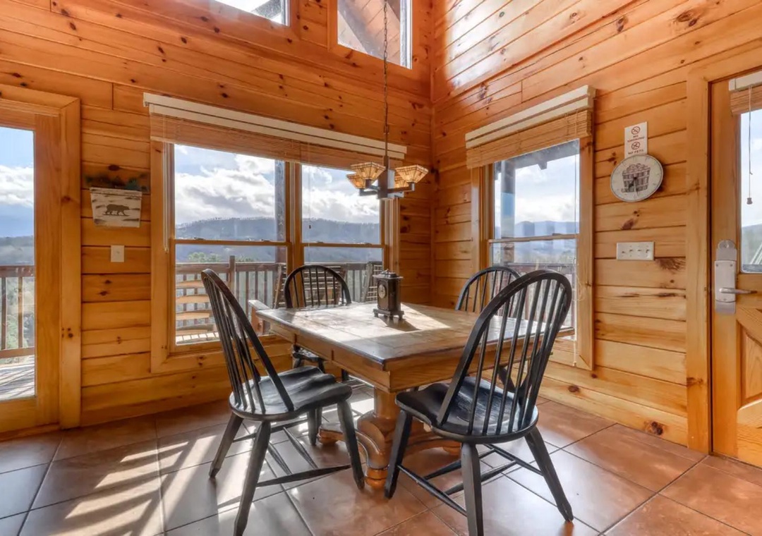 Gather around the dining table and savor meals with sweeping mountain vistas through expansive windows. The warm wood-paneled interior and vaulted ceilings create a cozy yet airy atmosphere for your mountain retreat.