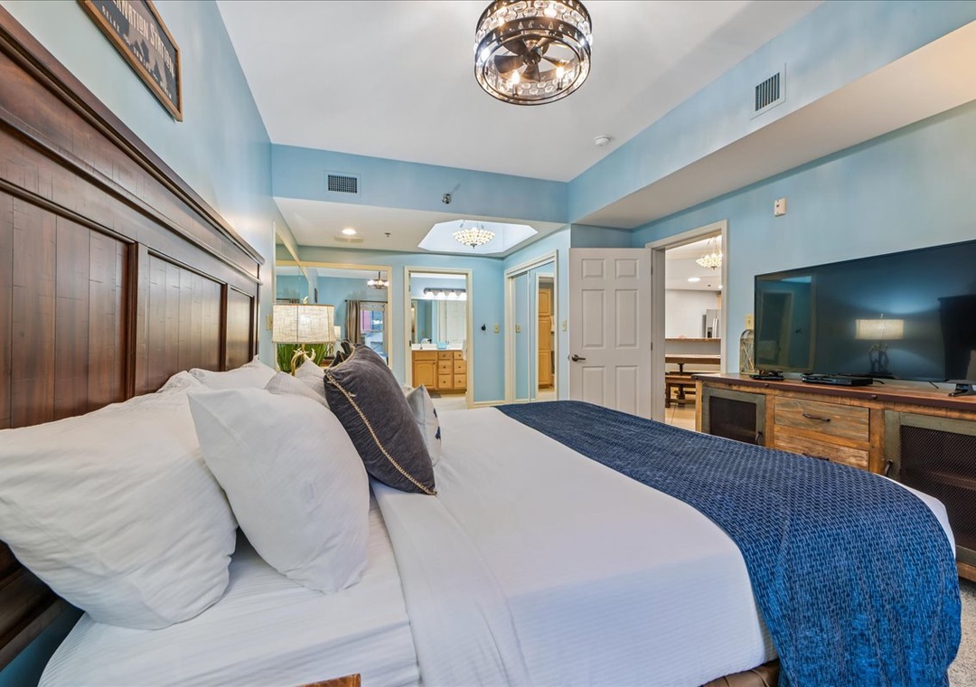 Sink into crisp white linens beneath sparkling crystal chandeliers in your serene blue-walled sanctuary, where comfort meets coastal elegance.