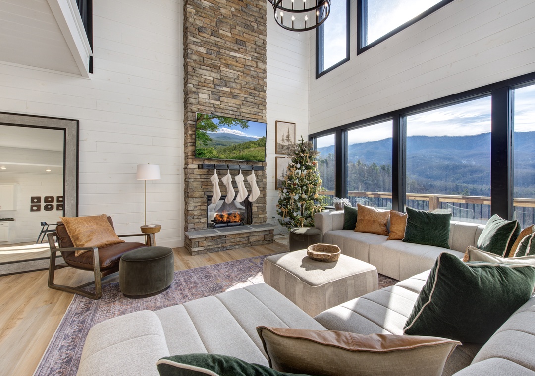 Unwind in your spacious living room with soaring ceilings, stone fireplace, and panoramic mountain views through floor-to-ceiling windows.