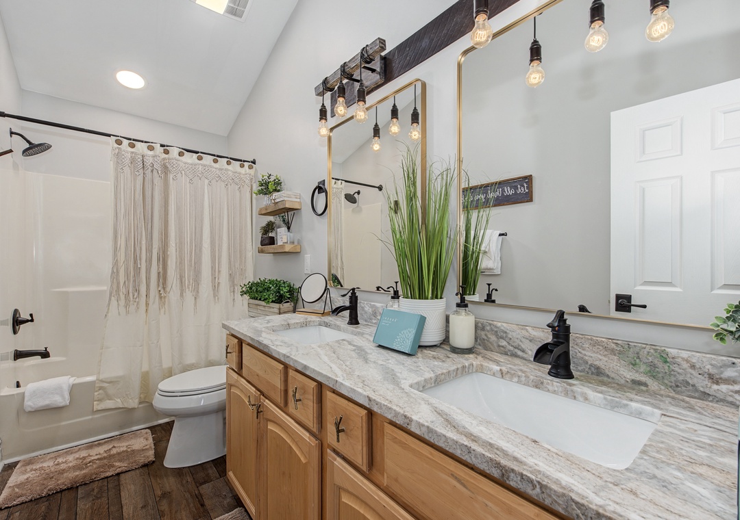 Unwind in this stylish bathroom featuring marble countertops, warm wood vanity, and elegant pendant lighting that creates your perfect spa-like retreat.