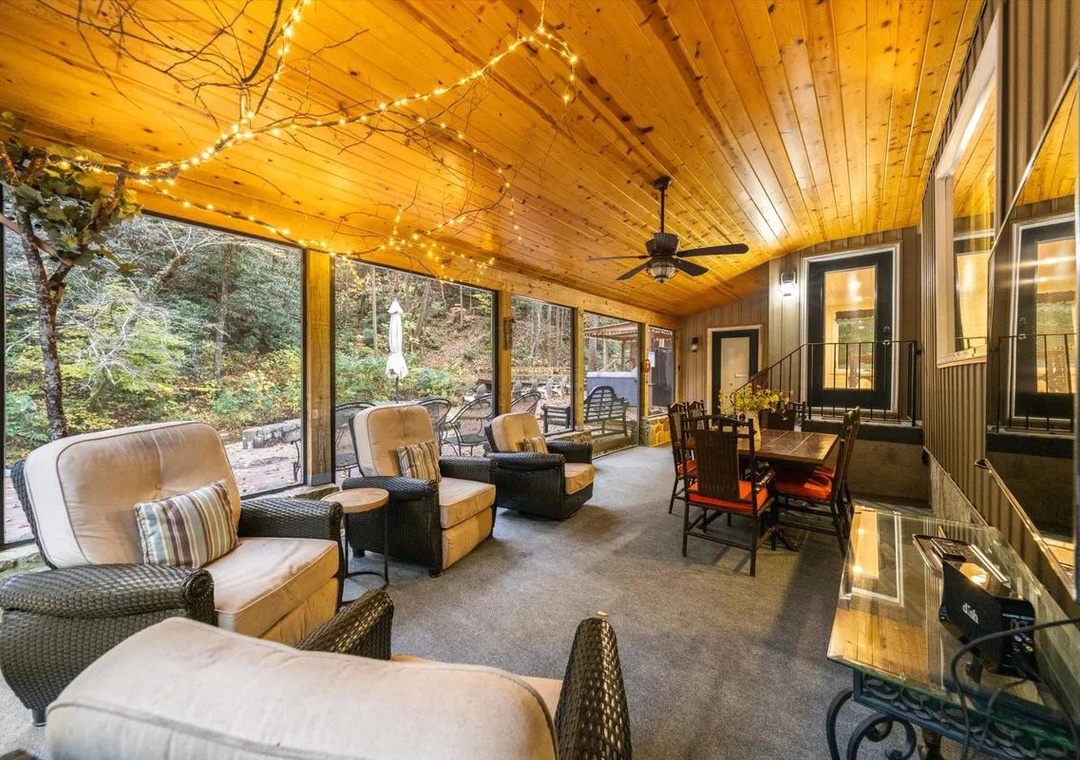 Unwind in your charming screened porch, where warm wood ceilings and twinkling lights frame peaceful forest views. Sink into plush seating for morning coffee or evening conversations surrounded by nature.