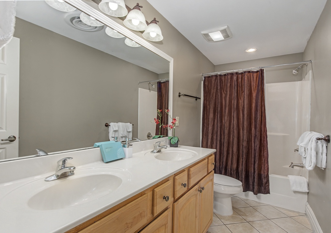 Refresh in your spacious bathroom featuring dual sinks, elegant vanity lighting, and a relaxing tub-shower combo for ultimate comfort.