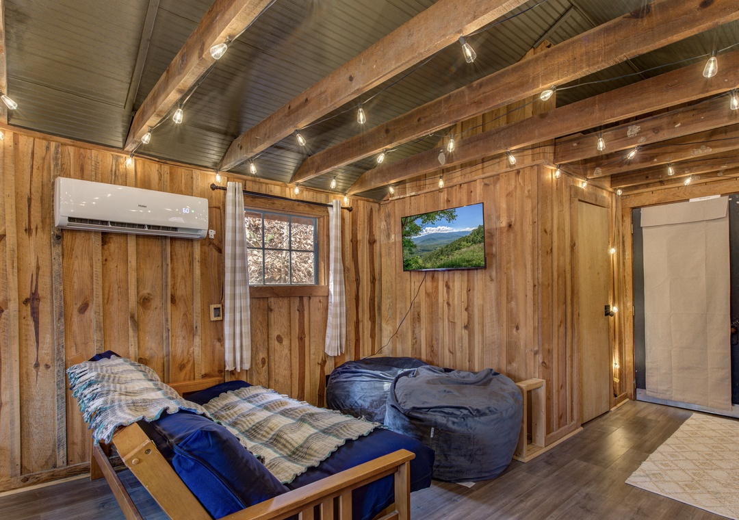 Unwind in your cozy cabin retreat with exposed beams, twinkling string lights, and plaid bedding for the perfect mountain escape.