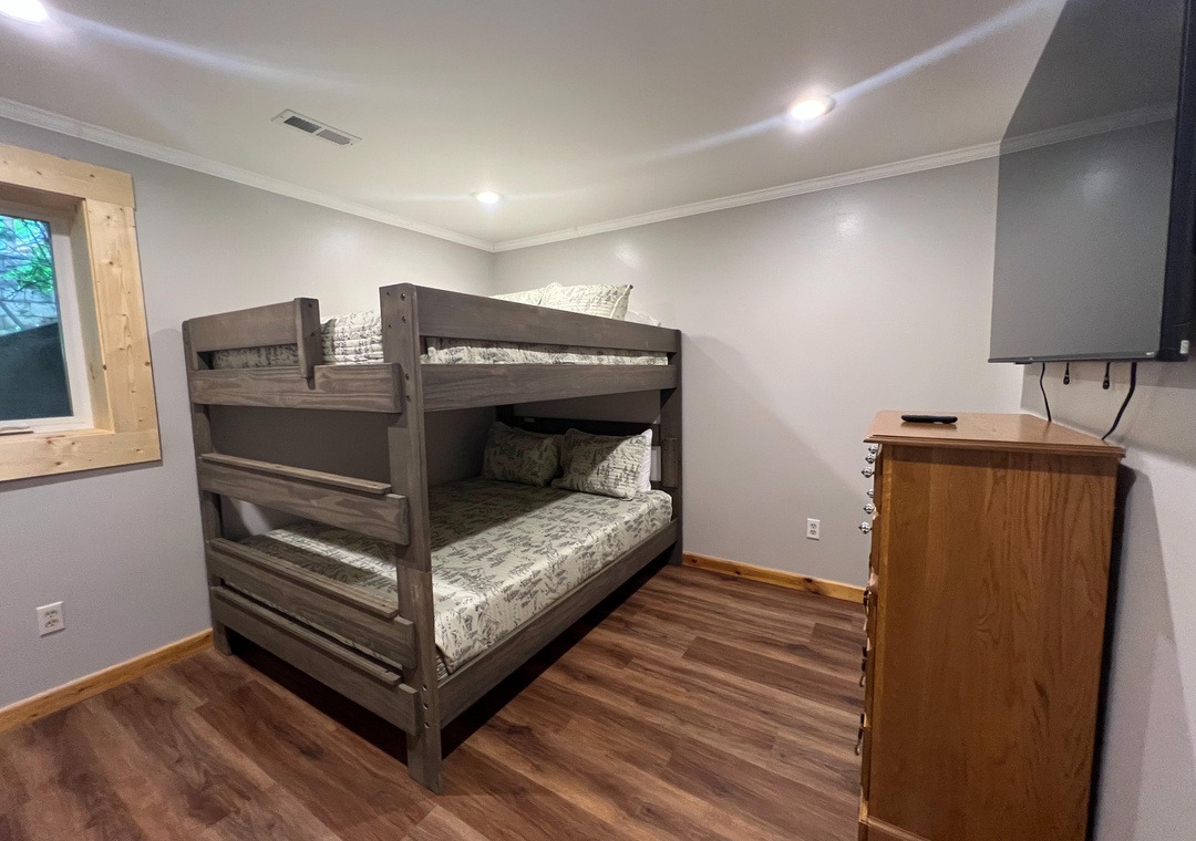 Your cozy bunk room with rustic wooden bunks and warm hardwood floors offers a comfortable retreat for kids or extra guests.