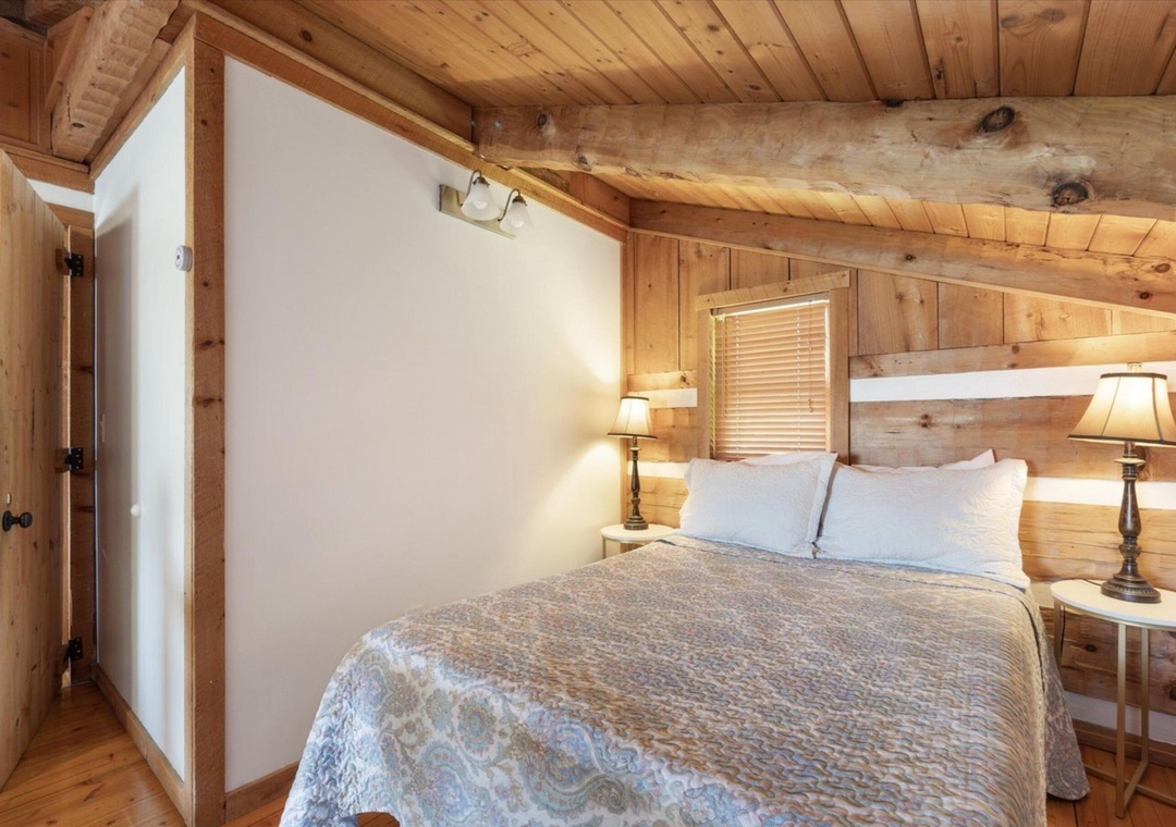 Drift off peacefully in your cozy log cabin bedroom, where rustic pine walls and warm bedside lighting create the perfect mountain retreat atmosphere.