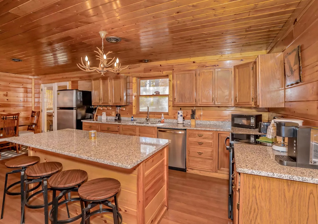 Cook family meals in your spacious rustic kitchen featuring granite countertops, modern appliances, and a cozy breakfast bar under warm cabin lighting.