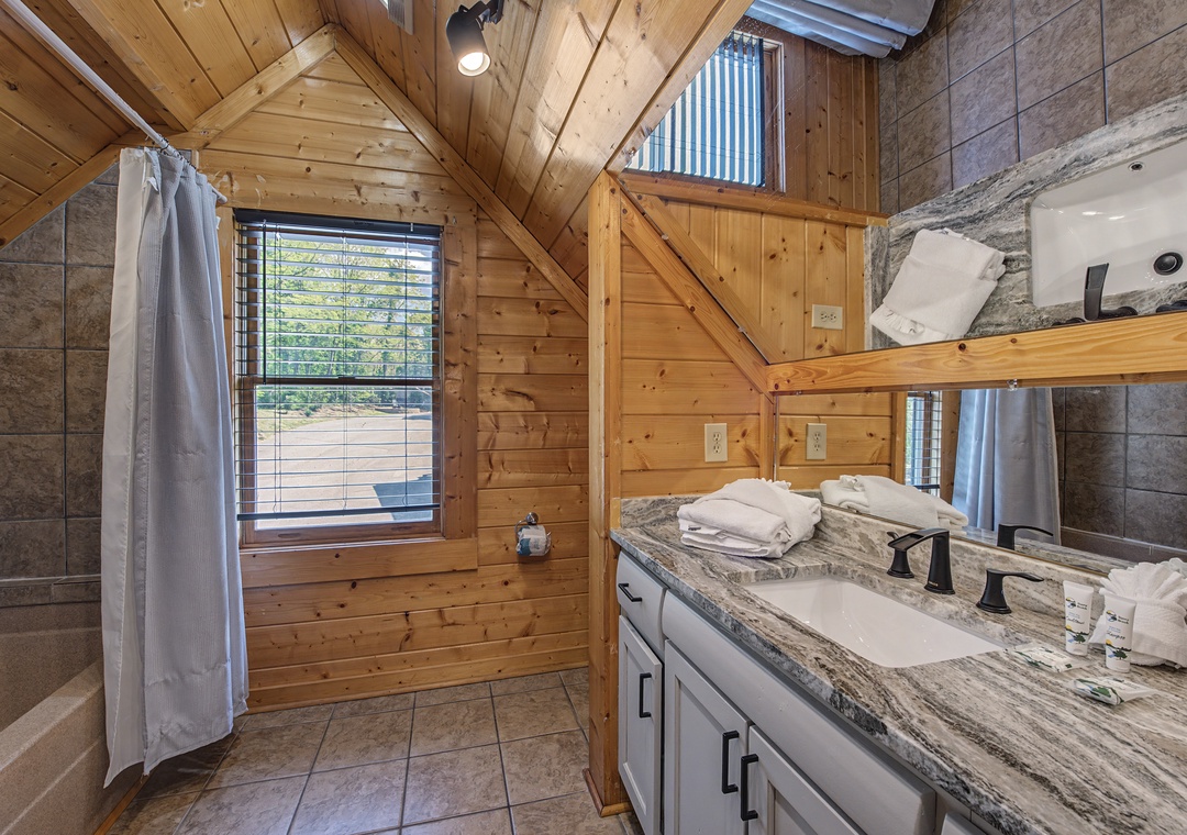 Unwind in your rustic bathroom featuring warm wood beams, marble counters, and fluffy towels waiting for your relaxing soak.