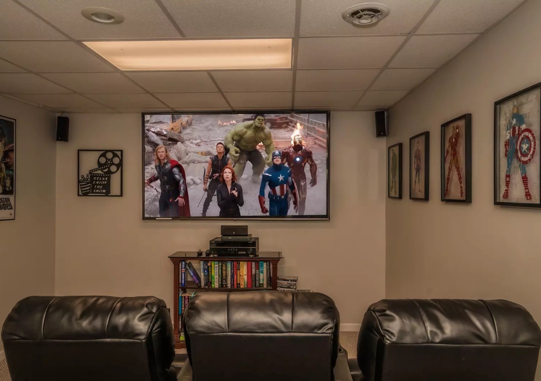 Your private movie theater awaits with plush leather seating, superhero artwork, and a massive screen for epic movie nights.