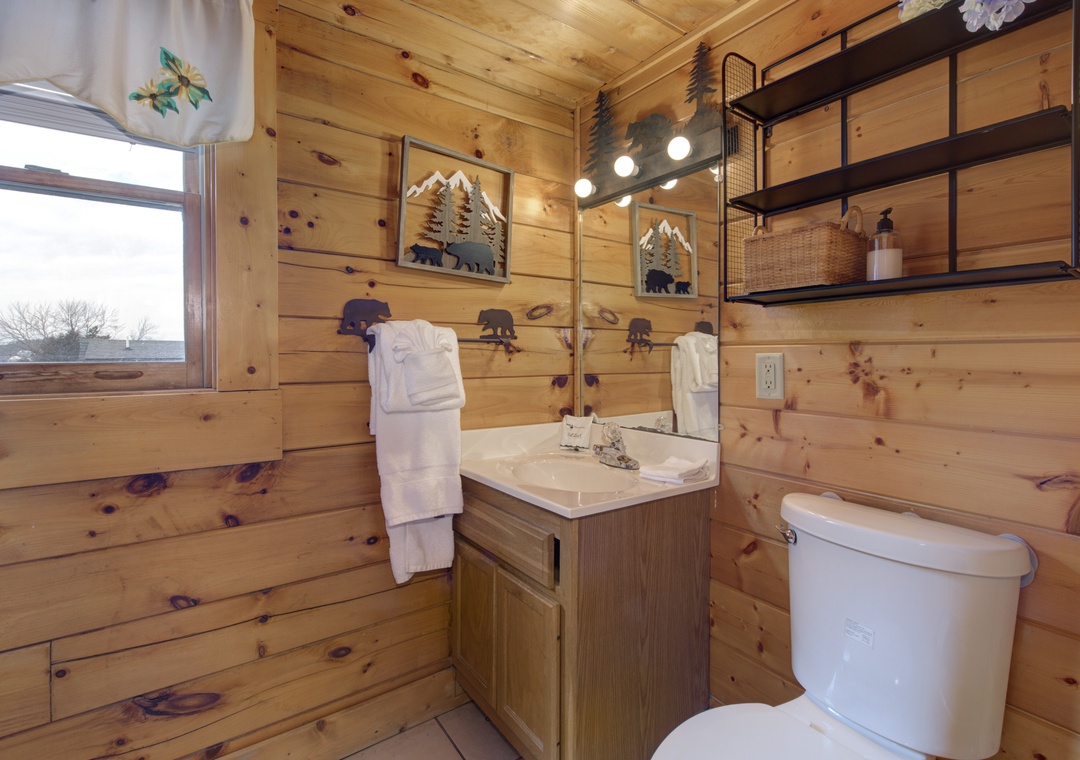 Step into your charming rustic bathroom, where knotty pine walls and mountain-themed artwork create a cozy cabin atmosphere for your peaceful retreat.