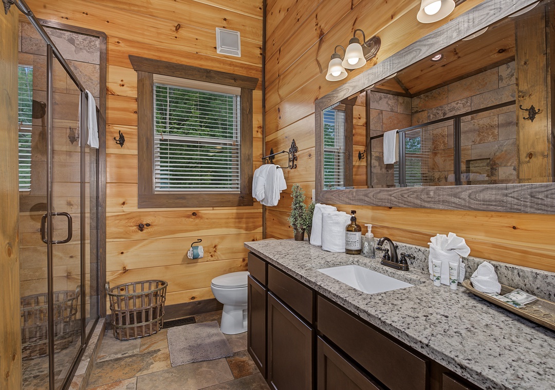 Your private bathroom blends rustic cabin charm with modern comfort—warm wood walls, a spacious walk-in shower, and plush towels waiting to help you unwind after a day of adventure.