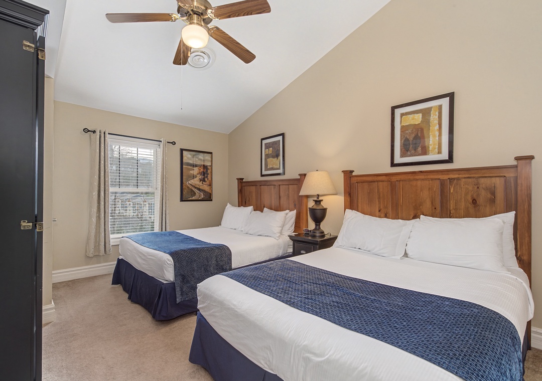 Rest peacefully in your cozy twin bedroom with comfortable beds, warm wood furnishings, and a gentle ceiling fan.
