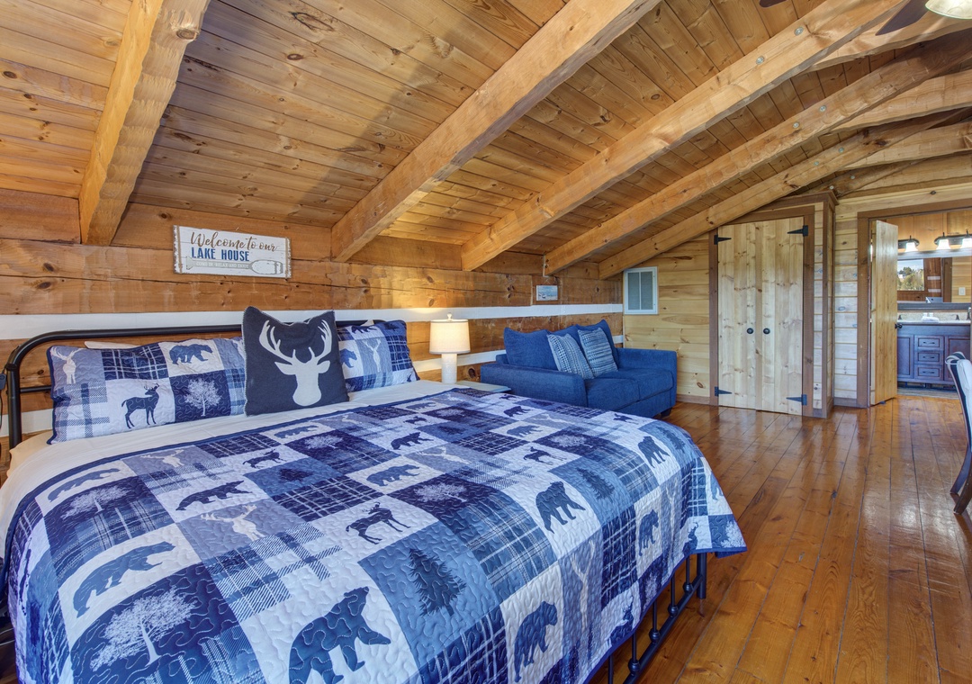 Unwind in your rustic loft bedroom where exposed beams and cozy plaid bedding create the perfect mountain retreat atmosphere.