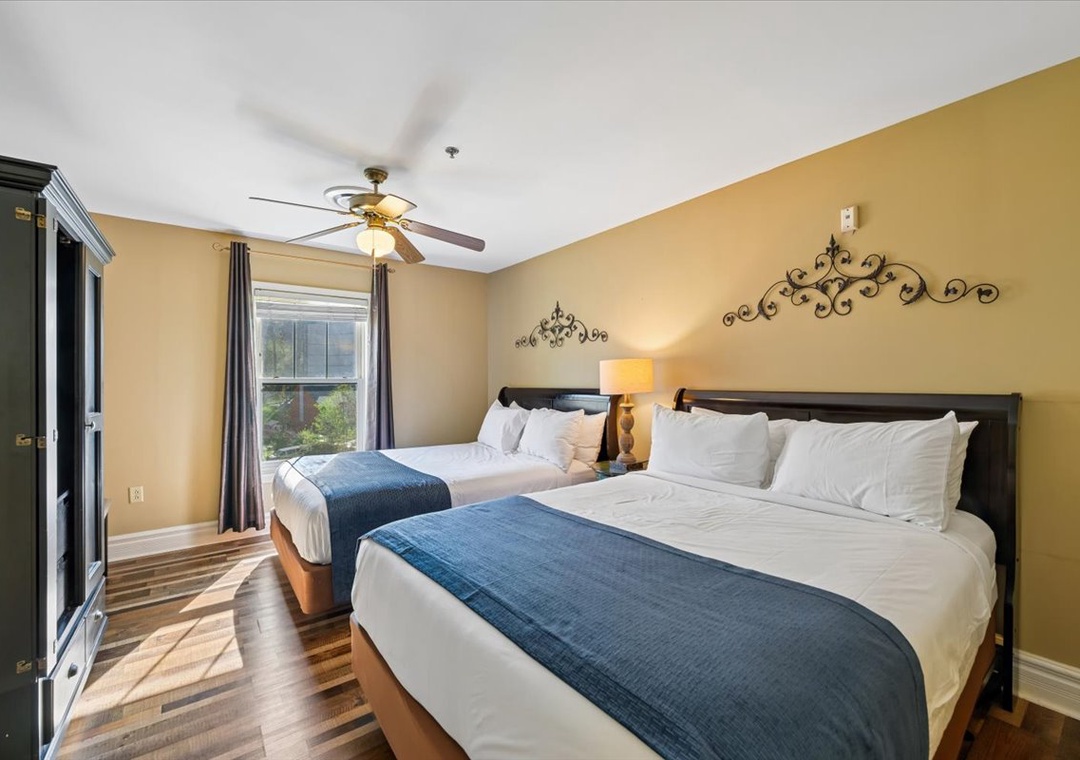 Your comfortable bedroom features two plush beds with crisp linens, elegant decor, and a ceiling fan for your relaxation.