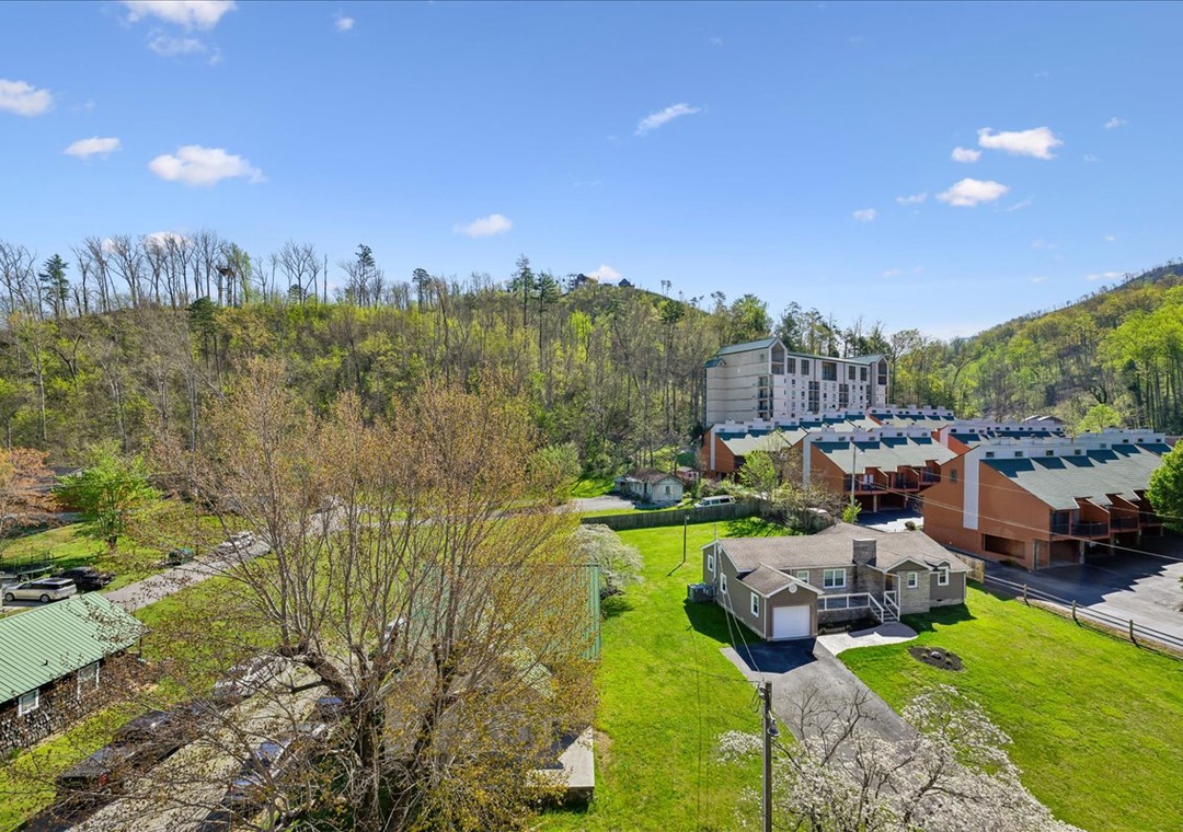 Aerial view showcasing the property nestled in rolling hills with lush spring greenery and modern resort buildings nearby.