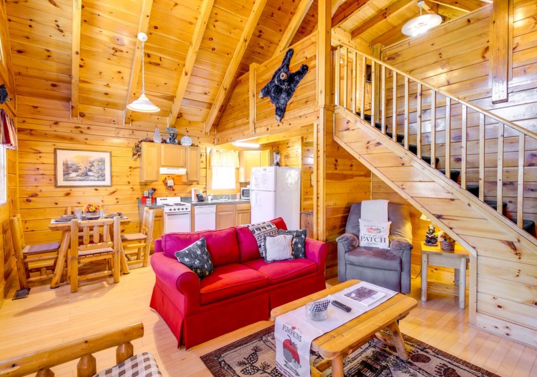 Cozy up in this charming wood cabin with vaulted ceilings, a bright red sofa, and rustic touches that make you feel right at home.