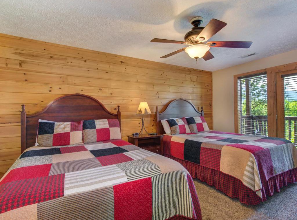 Relax in this charming twin bedroom with rustic wood walls and cheerful quilted bedding. The ceiling fan keeps you comfortable while you enjoy forest views.