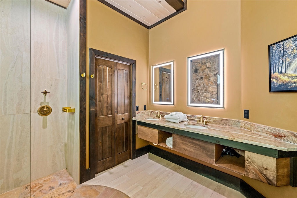 Unwind in your private bathroom featuring a spacious walk-in shower, dual vanities with elegant stone countertops, and soft towels waiting for you—all bathed in warm natural light.