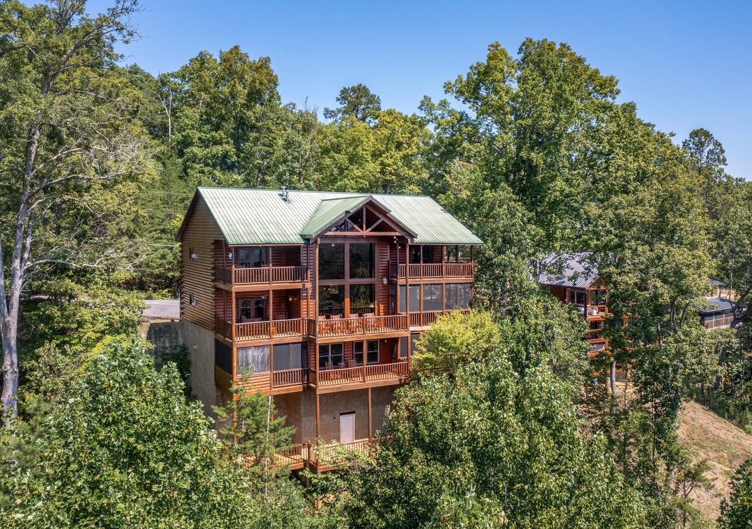 A spacious mountain cabin retreat nestled among mature hardwoods, featuring multiple levels of wraparound decks and expansive windows that embrace the surrounding forest.