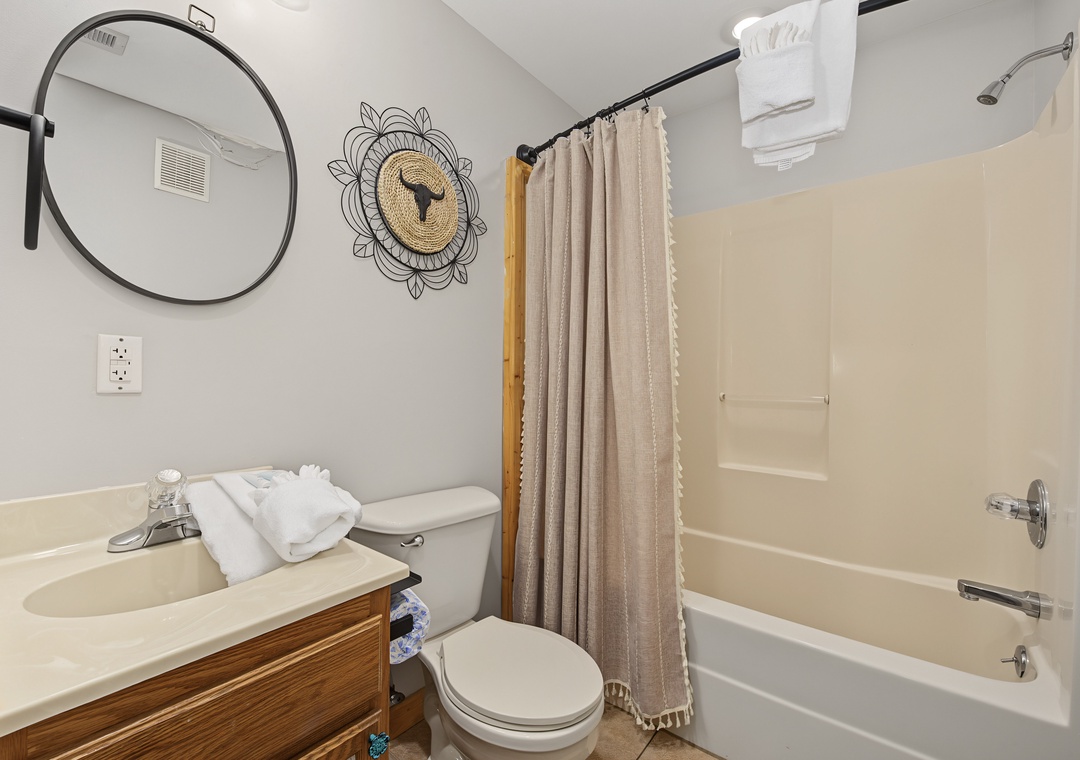 Step into your private retreat, where a sleek circular mirror and charming wall art add personality. Crisp towels await, and the tub/shower combo invites you to unwind after a day of adventure.