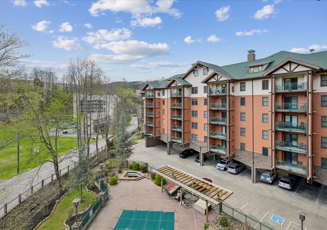Multi-story resort buildings with green roofs overlook scenic mountain landscape and recreational facilities.