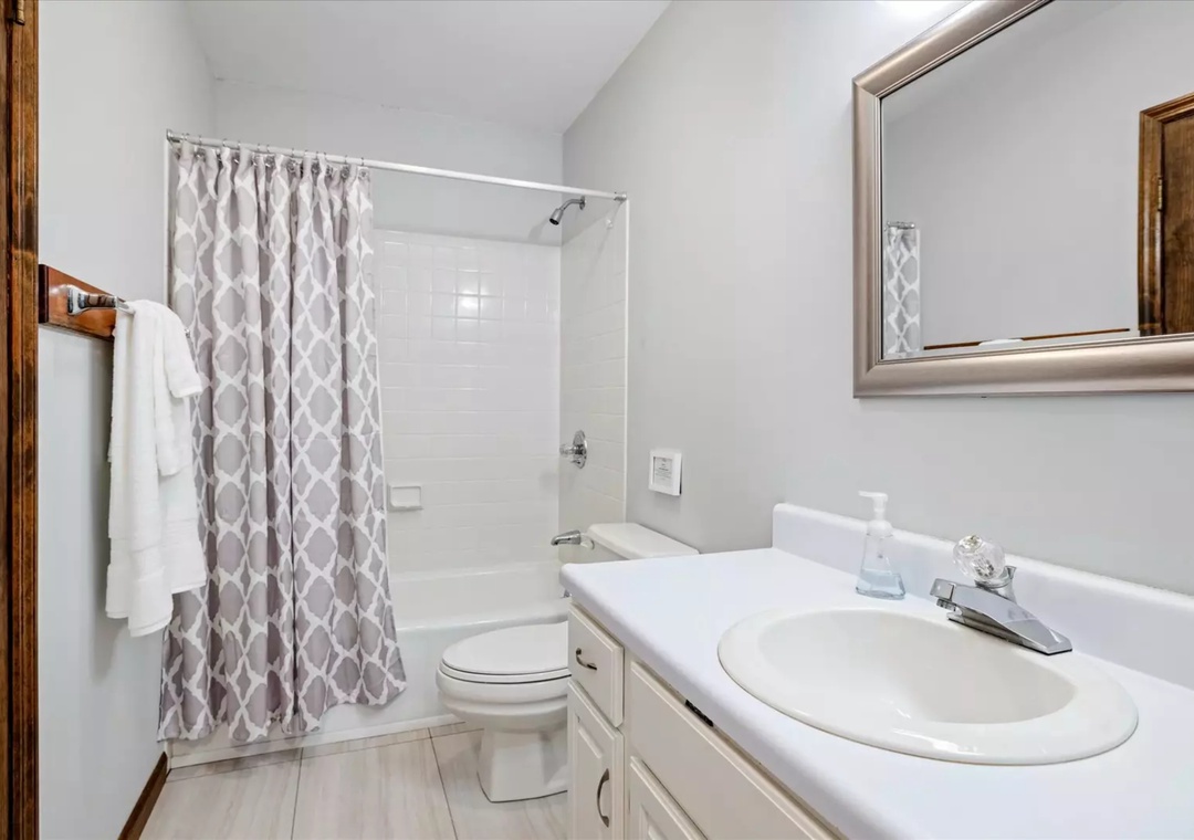 Step into your bright, clean bathroom with modern fixtures and stylish geometric shower curtain. Fresh towels await your arrival.
