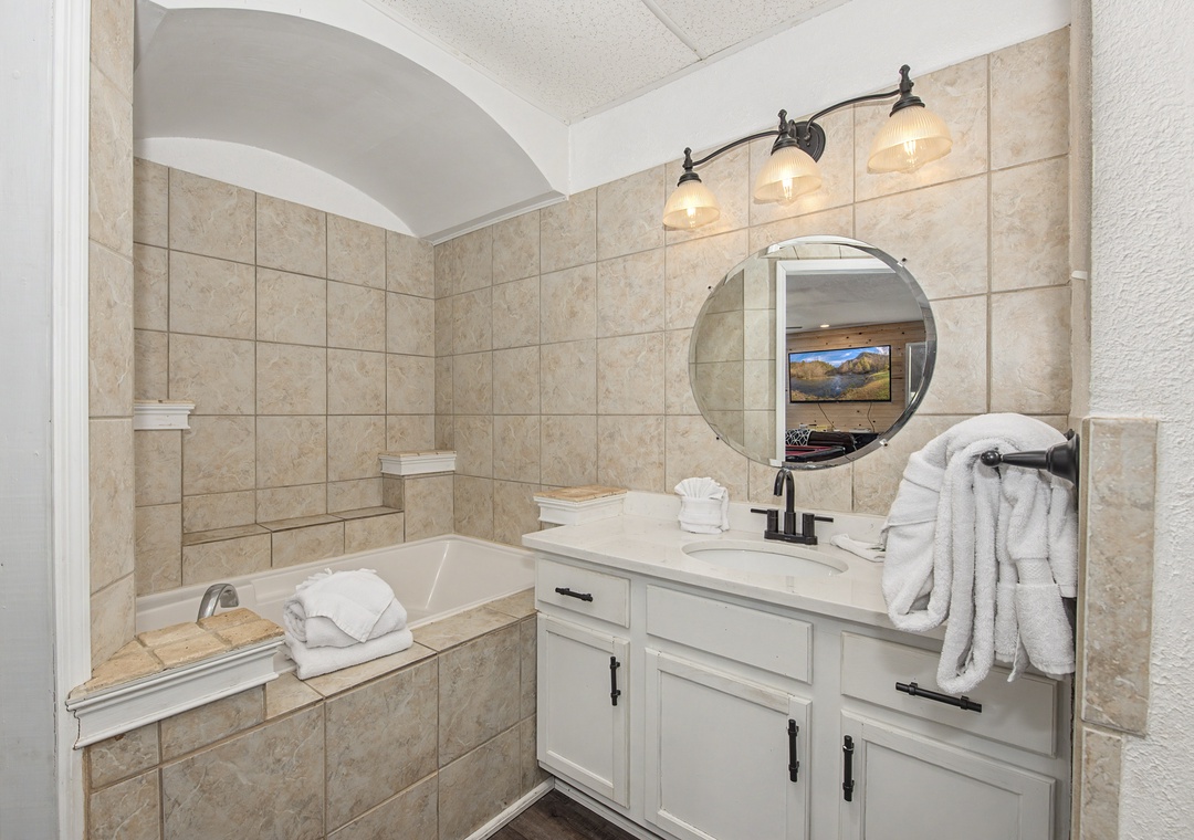 Unwind in your elegant bathroom featuring a deep soaking tub, warm lighting, and plush towels for the perfect relaxation retreat.