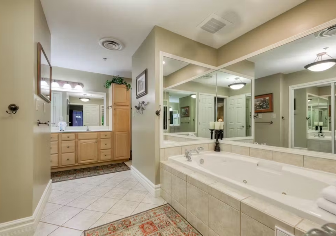 Unwind in your luxurious spa-style bathroom featuring a jetted soaking tub, spacious vanities, and elegant tile work for ultimate relaxation.