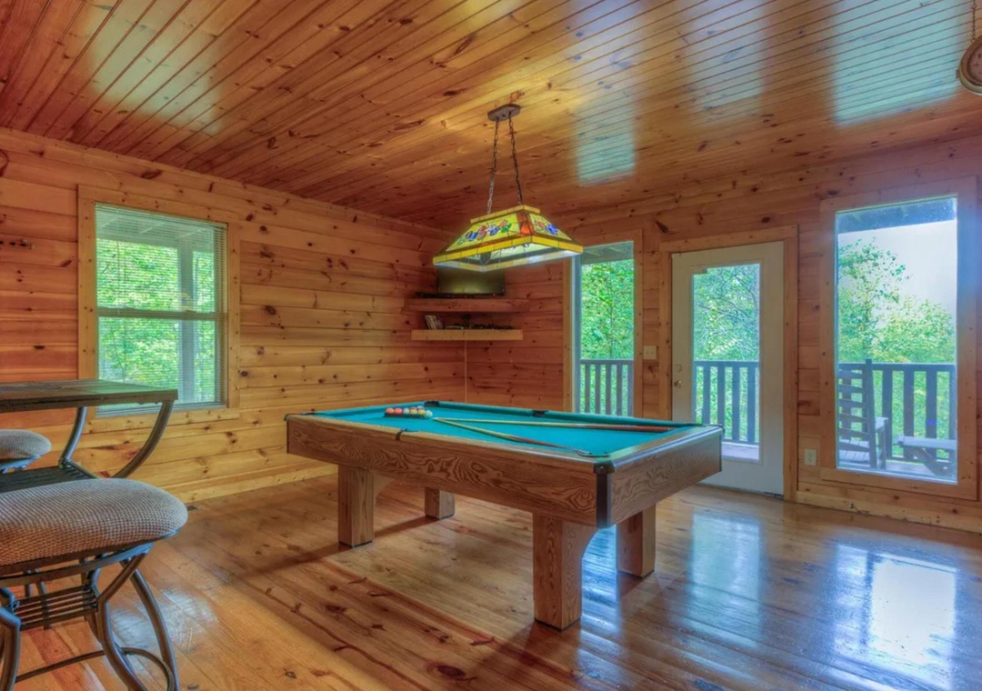 Your own private game room awaits, with warm wood tones, a pool table for friendly competition, and doors opening to treetop views—perfect for unwinding.