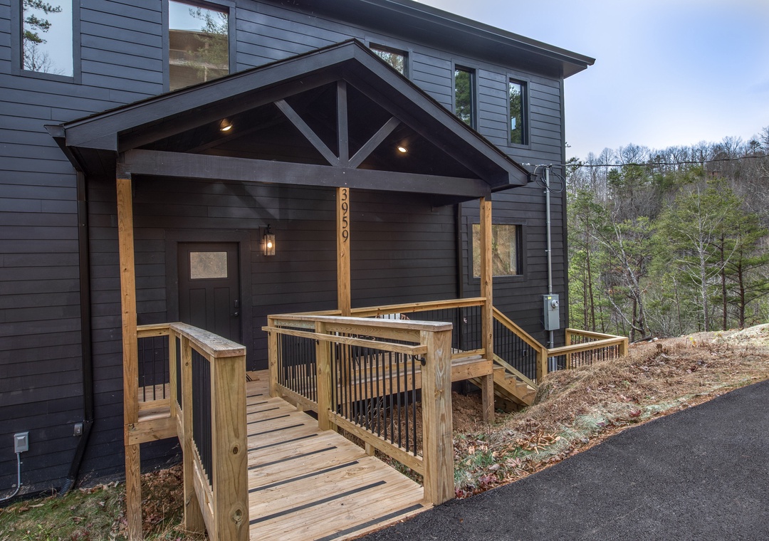 Modern mountain retreat with welcoming covered entrance and natural wood accents nestled among peaceful wooded surroundings.