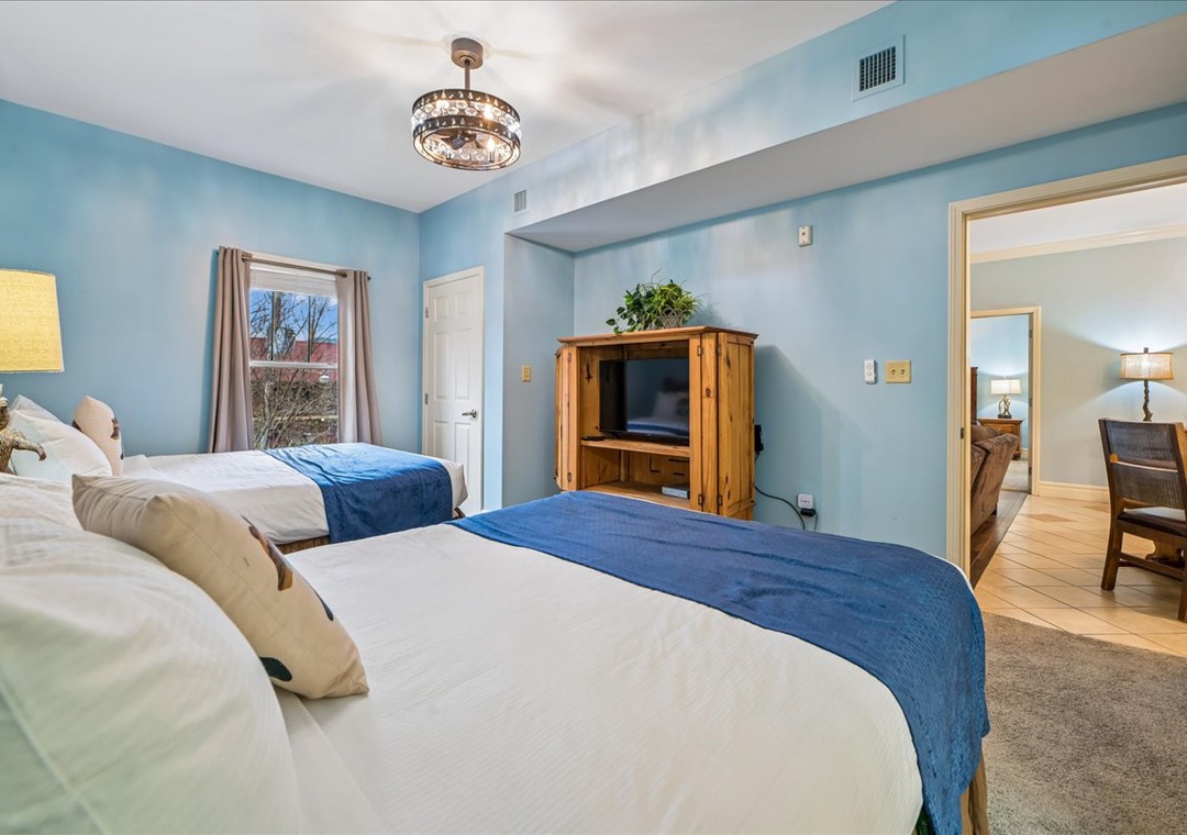 Relax in your spacious bedroom with twin beds, elegant lighting, and entertainment center—perfect for unwinding after exploring.