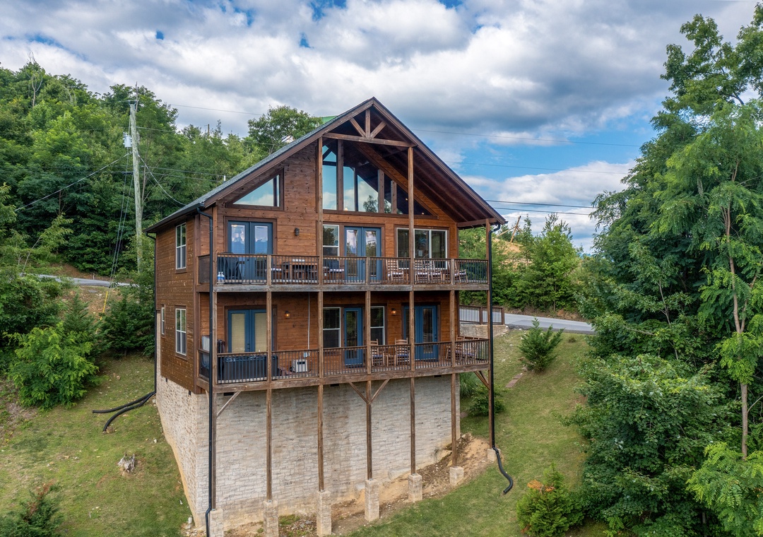 A striking multi-level cabin nestled in lush wooded hills, featuring spacious balconies and floor-to-ceiling windows that showcase the natural surroundings.